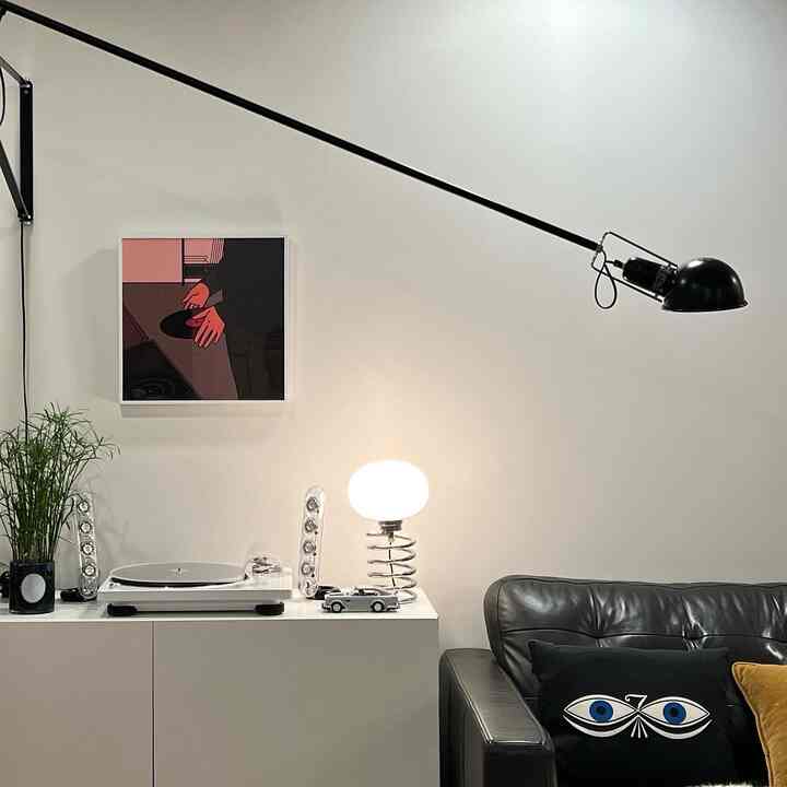 White and black toned living room featuring a white cabinet with turntable and spiral table lamp, creating a stylish hobby zone