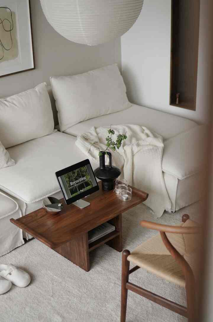 Warm natural-toned living room featuring ivory sectional sofa and wooden coffee table with a cozy atmosphere