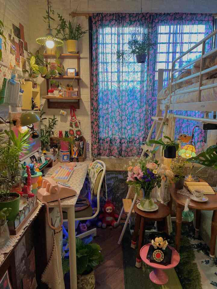 A small room in pink and brown tones featuring a bunk bed, desk, plants, and fresh flowers creating a warm atmosphere