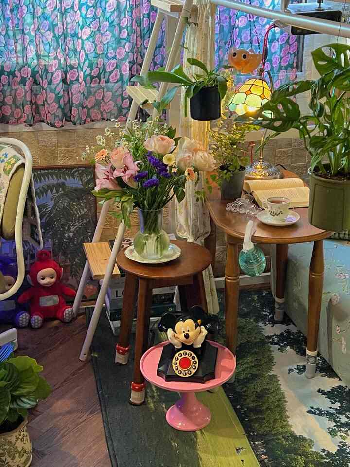 Cozy small room with floral curtains, wooden side tables and stools, assorted plants and flowers creating a warm atmosphere