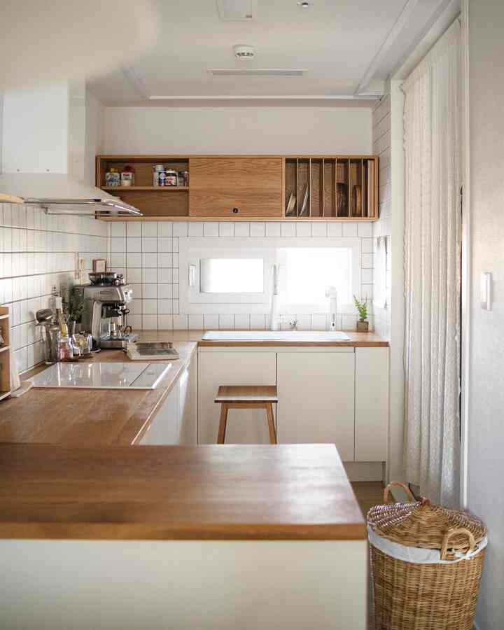 Cozy kitchen featuring natural wood tones and white tiled walls, with a coffee machine and organized dish storage visible