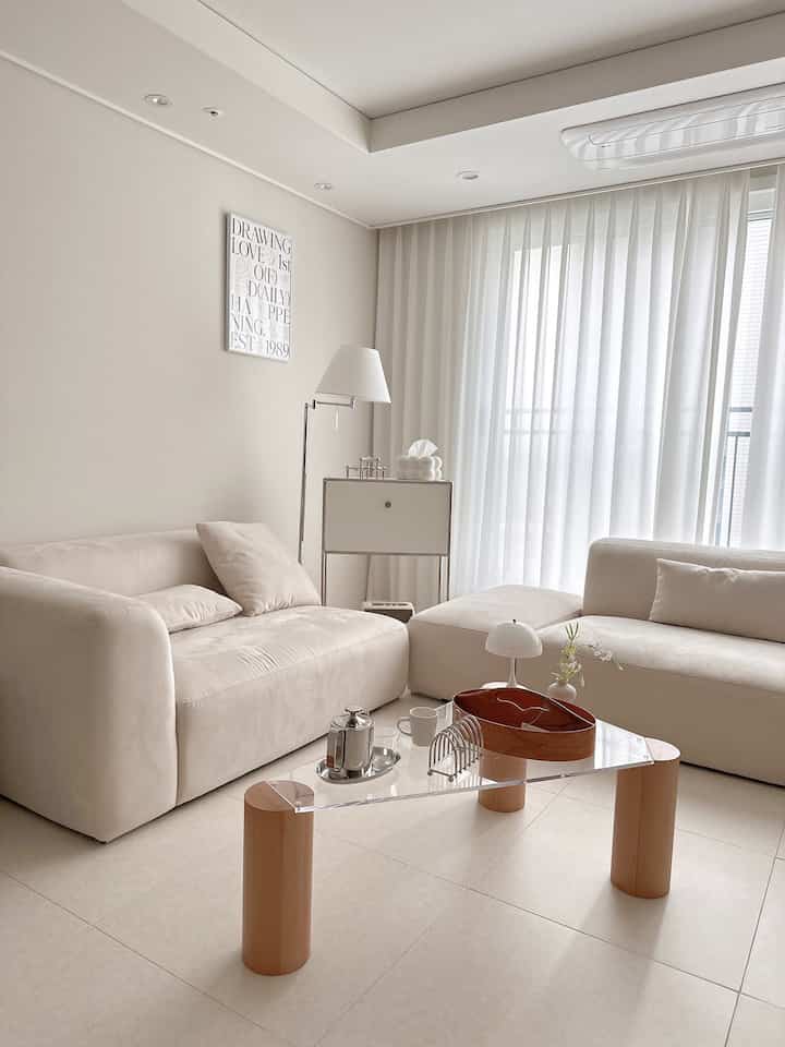 Beige-toned living room featuring two sofas and a wood-tone coffee table in a minimal and natural setting