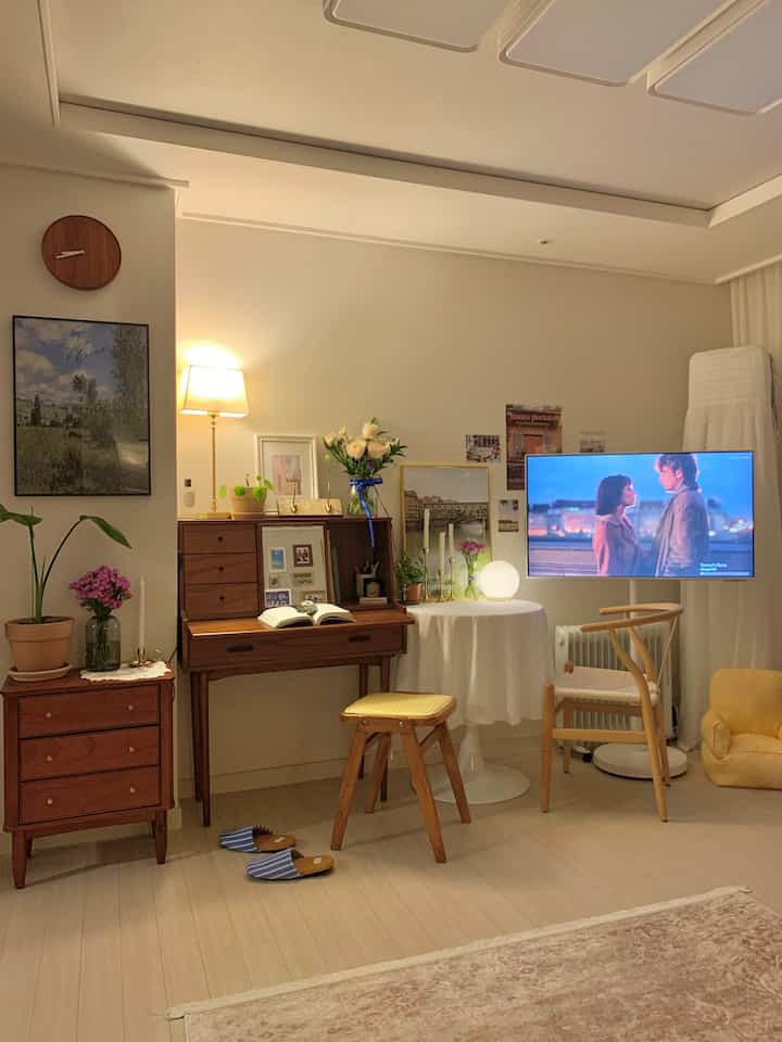 White and wood tone vintage living room featuring a wooden desk and TV creating a warm atmosphere