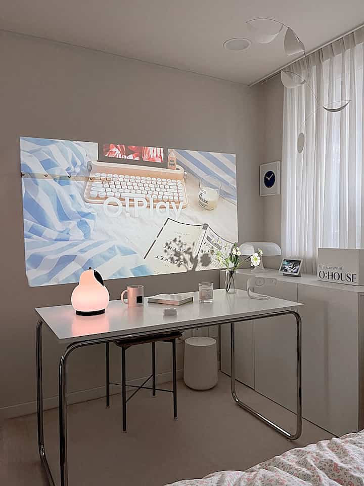 White-toned compact room featuring a simple steel frame desk and table lamp in a cozy study space