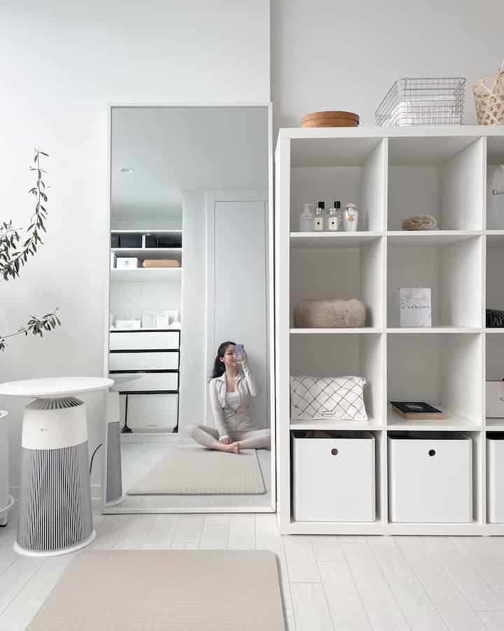 Bright and calm white-toned walk-in closet featuring neat shelving and a yoga mat in a minimalist interior