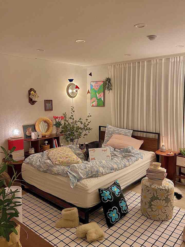 Natural toned bedroom featuring a bed with a cat, rug, and plants creating a cozy atmosphere