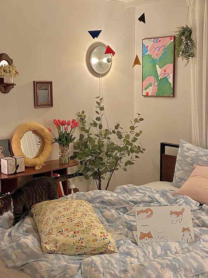 ベージュトーンの寝室、雲柄の掛け布団とペットの猫がいる雰囲気のある空間