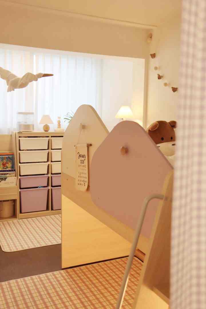 柔らかなベージュとラベンダーの色調の小さな子供部屋で、二段ベッドとカーテン仕切り、チェストが温かみのある雰囲気を作り出している