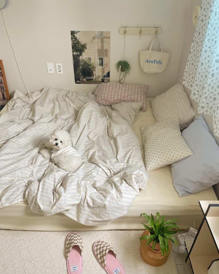 ベージュとホワイトの落ち着いた寝室、快適な寝具とペットの犬が配置された自然で居心地の良いインテリア