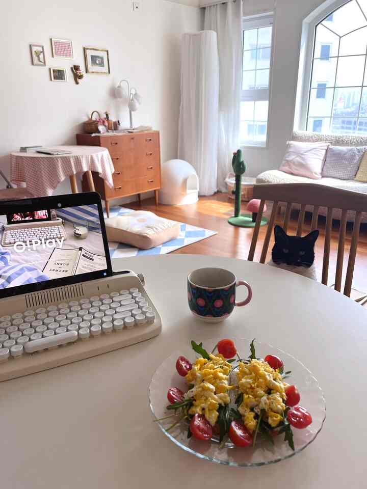 白と木目調が調和したリビング、ソファと猫用のスクラッチャーが配置された居心地のいい空間