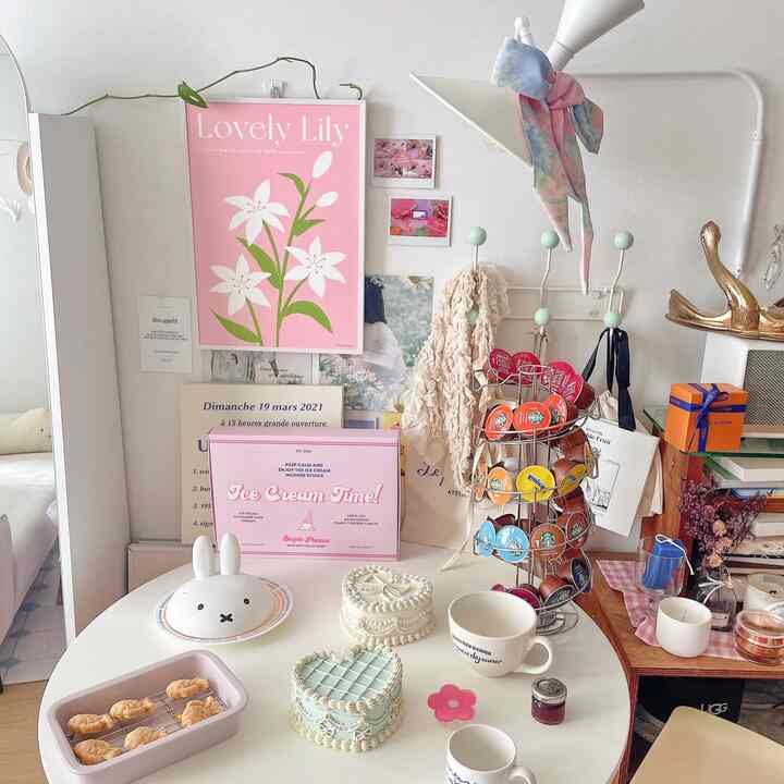 Simple and cozy home cafe space with white walls and table, featuring a pink floral poster and a coffee capsule carousel on the table