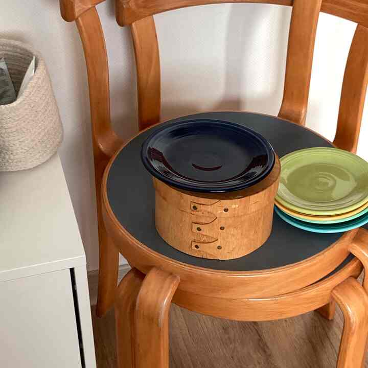 Natural wood tone dining chair featuring vintage-style plates in a simple setting