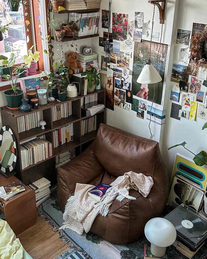 Natural-toned living room reading space featuring brown bean bag chair, bookshelf, plants, and wall decor