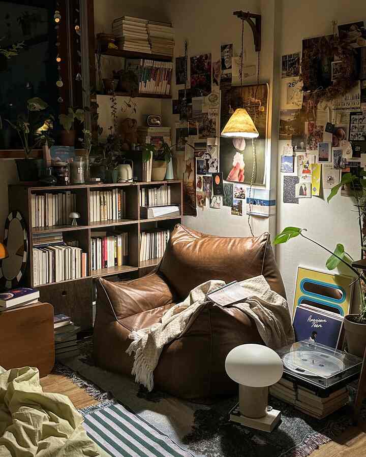 暖かいナチュラルカラーのワンルーム読書スペース、ビーンバッグと本棚、ペンダントライトが配置された雰囲気のあるインテリア