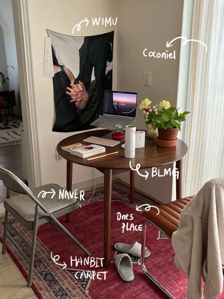 木目調の丸テーブルと2脚の椅子、赤いラグと植物が配置された雰囲気のあるホームオフィス空間