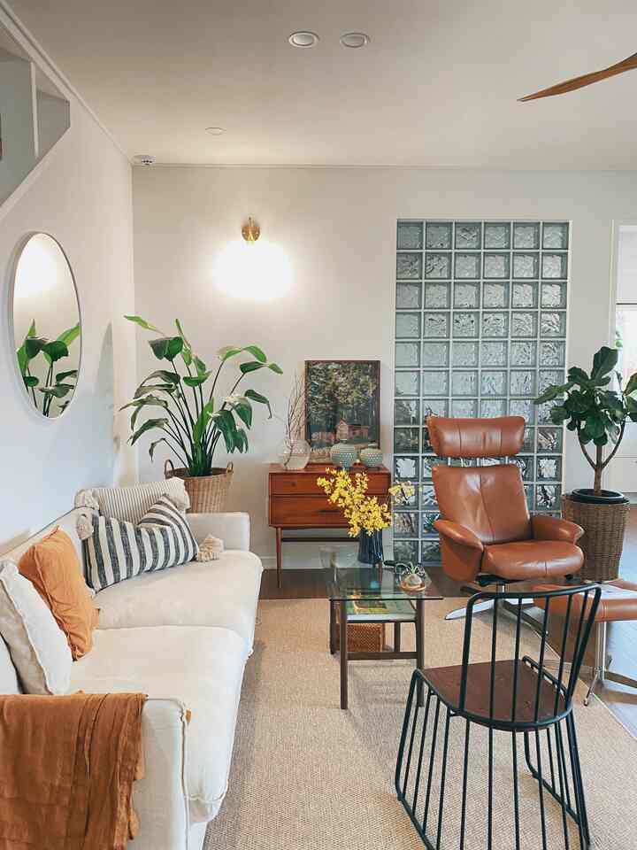 Natural-toned first-floor living room featuring white sofa, leather recliner, and indoor plants with a cozy ambiance