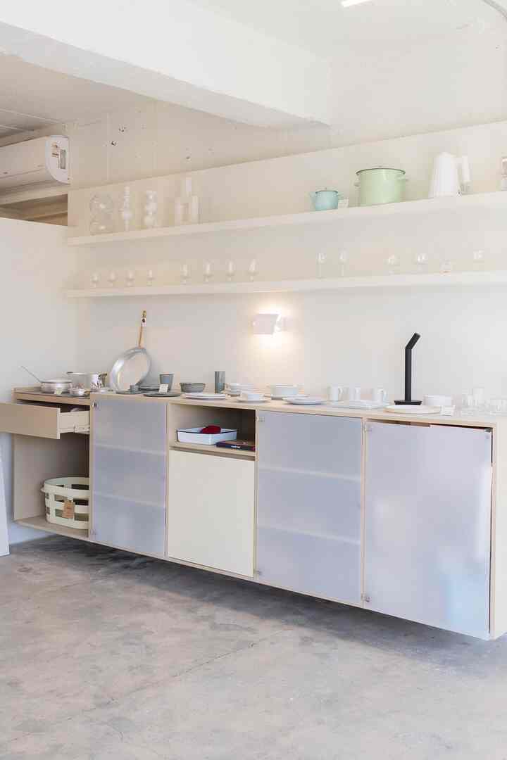 A white and pastel-tone kitchen space featuring objets and kitchenware neatly arranged with a minimalistic atmosphere