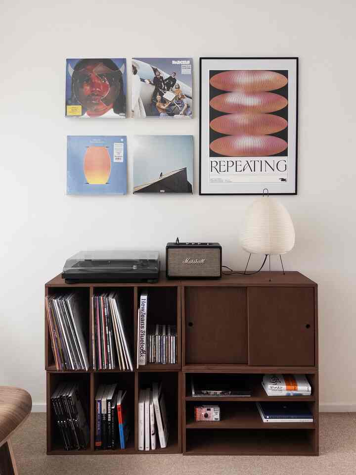 Light brown storage cabinet against white wall, featuring vintage vinyl records and posters in a modern Nordic interior
