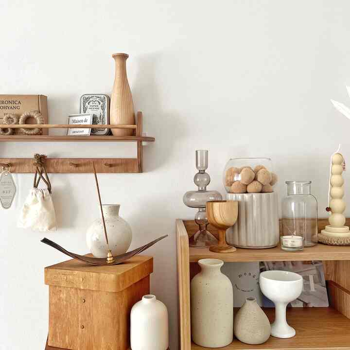 Cozy beige and wood tone dining room featuring diverse ceramic objets and storage shelves in a natural style interior