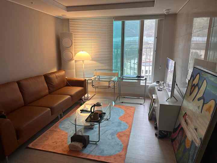 温かみのあるブラウンとブルーのモダンで自然な雰囲気のリビング、ブラウンレザーのソファとガラスのコーヒーテーブルが調和した空間