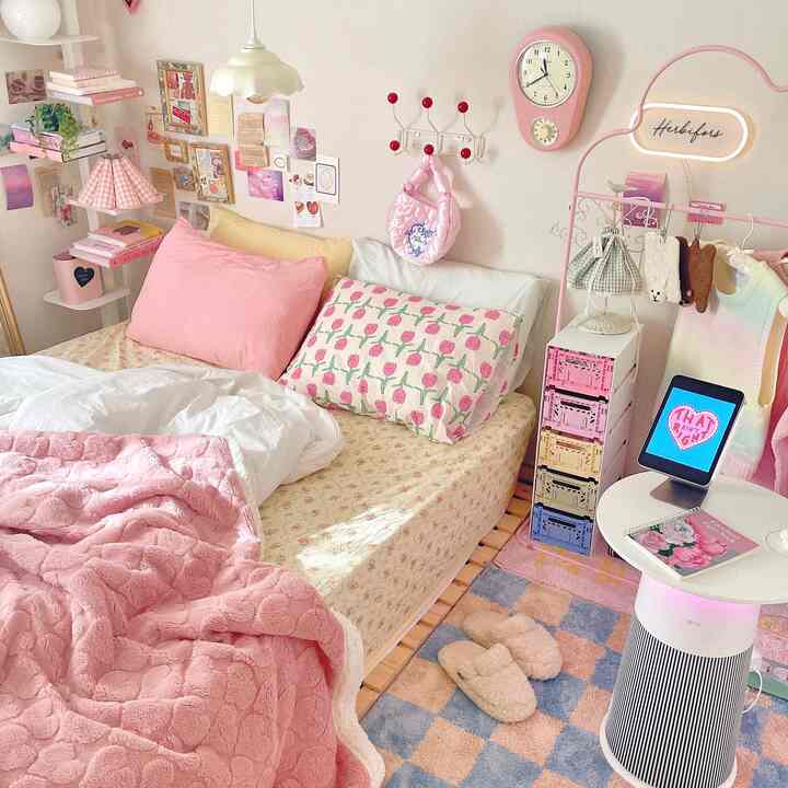 柔らかなピンクとホワイトのトーンでまとめられたコンパクトな寝室、ベッドとカラフルな収納箱、温かみのあるラグが配置された雰囲気のあるインテリア