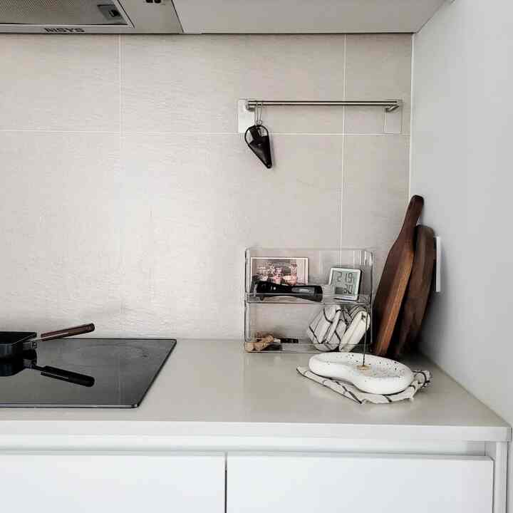 Simple kitchen in white and beige tones featuring walnut cutting boards and a digital thermo-hygrometer on a neat countertop