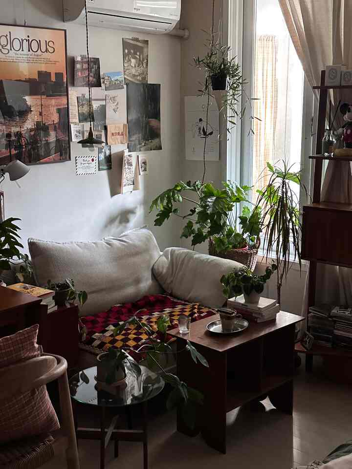 Cozy living room in soft white and brown natural tones, featuring sofa, coffee table, and abundant plants arranged harmoniously