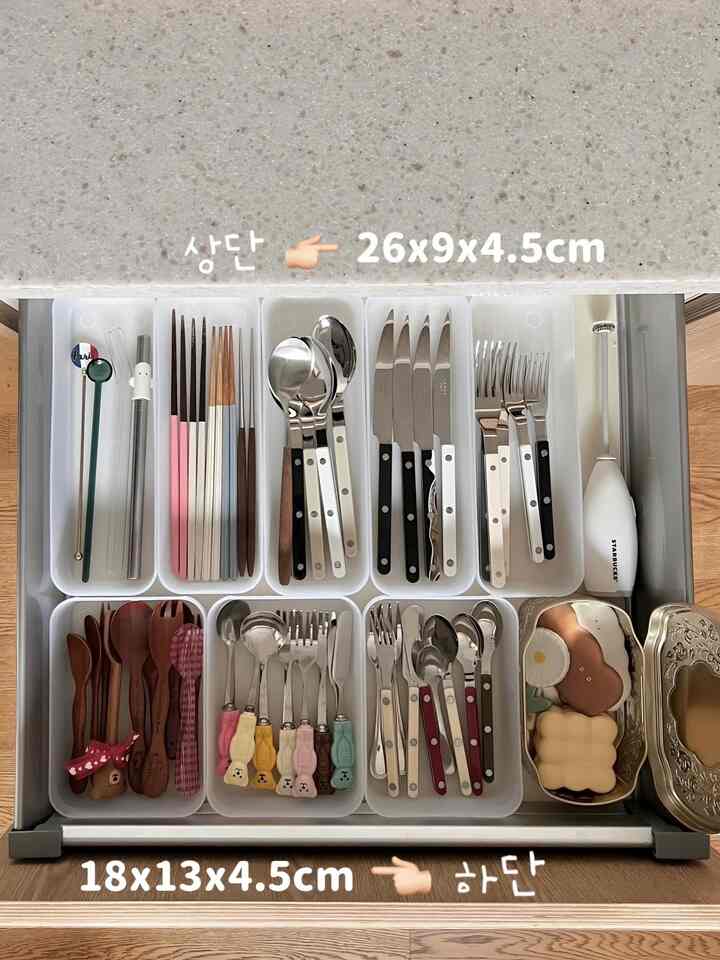 White tray-organized cutlery drawer featuring various spoon rests and a Starbucks milk frother in a neat kitchen space