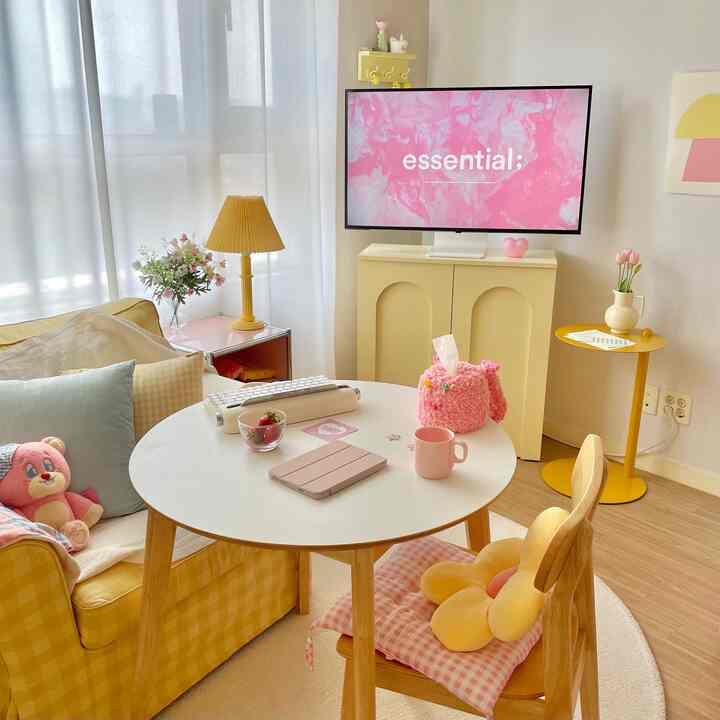 ピンクと黄色の色調が調和したリビング、円形テーブルと黄色のチェック柄ソファが明るく華やかな雰囲気のあるインテリア