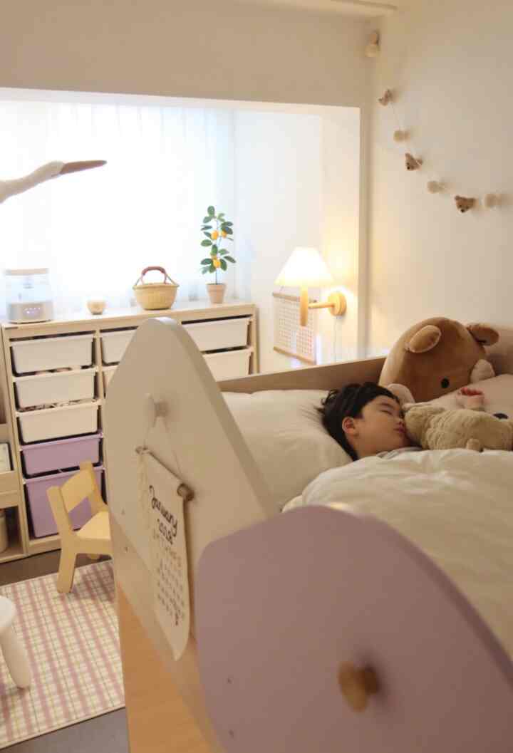 Bright natural-toned kids' room featuring a child's bed, garland, and wall sconce creating a cozy atmosphere