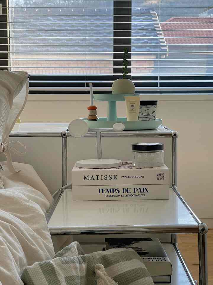 白と木目調の寝室、USMのサイドボードとソフトメランジ寝具セットが配置され、落ち着いた雰囲気のインテリア