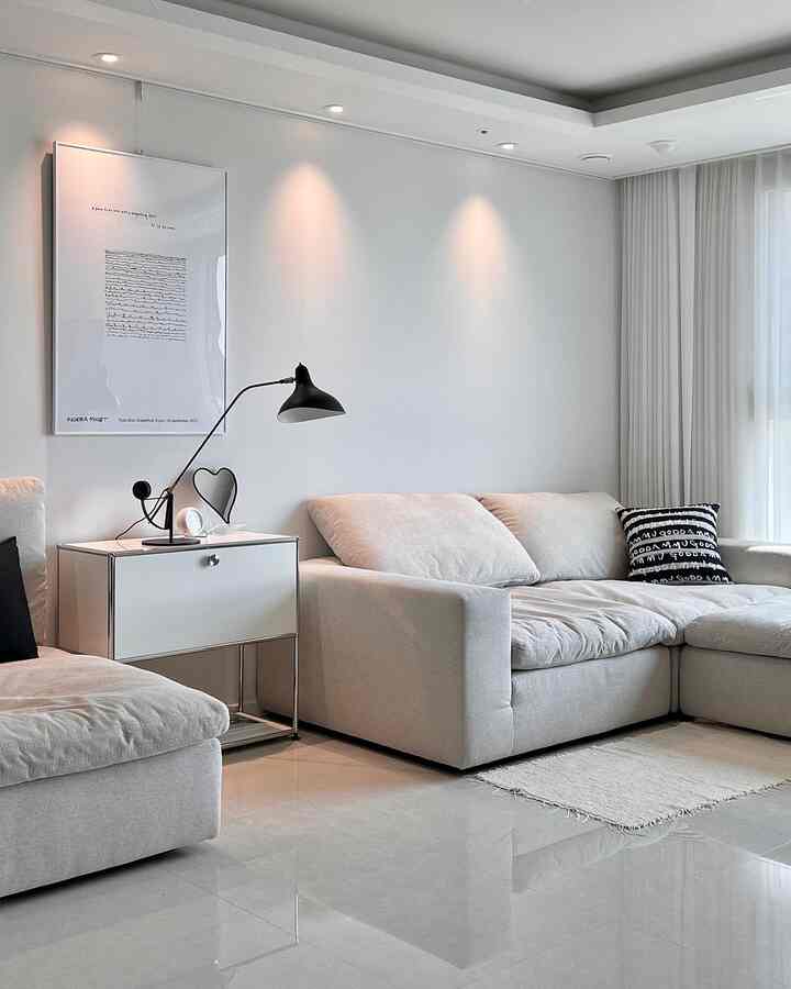 Bright white and gray toned modern living room featuring an L-shaped sofa, side table, and simple poster in a clean layout