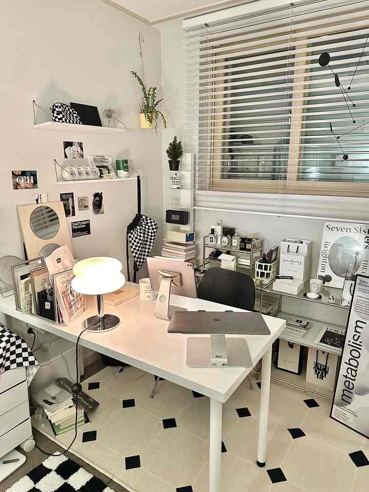 A white and black toned small home office featuring a clean desk and storage shelves in a simple modern interior