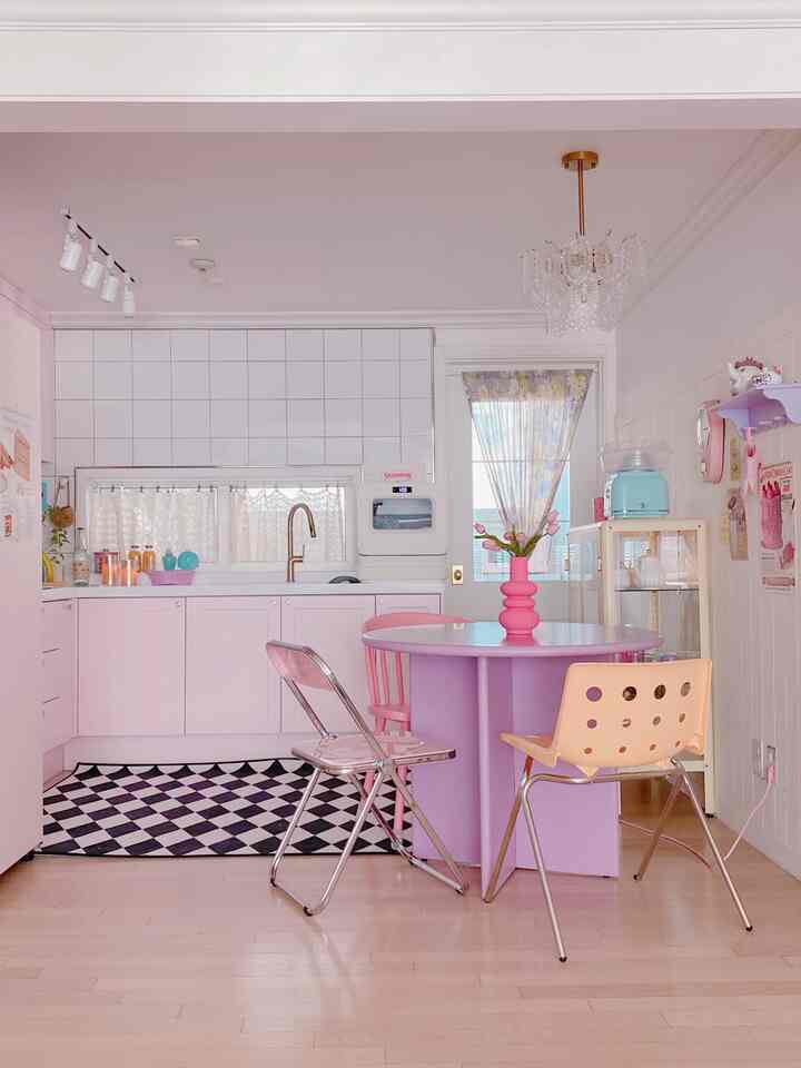Pink and purple kitchen featuring a round dining table with various chairs in a cozy home cafe setting