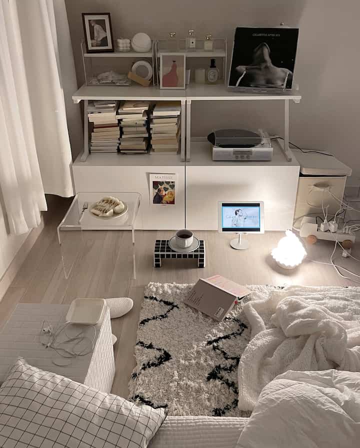 Natural modern bright bedroom music space featuring white storage units, a clear side table, turntable, and LP posters for a cozy vibe