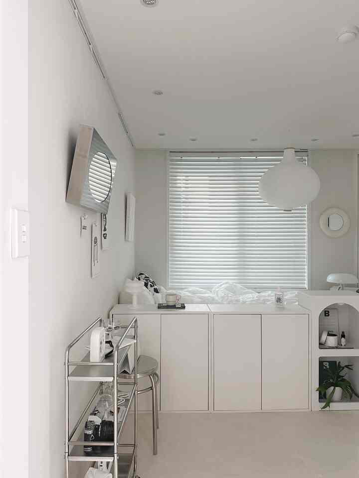 Modern bedroom space in white tones featuring steel shelving and white cabinets arranged neatly