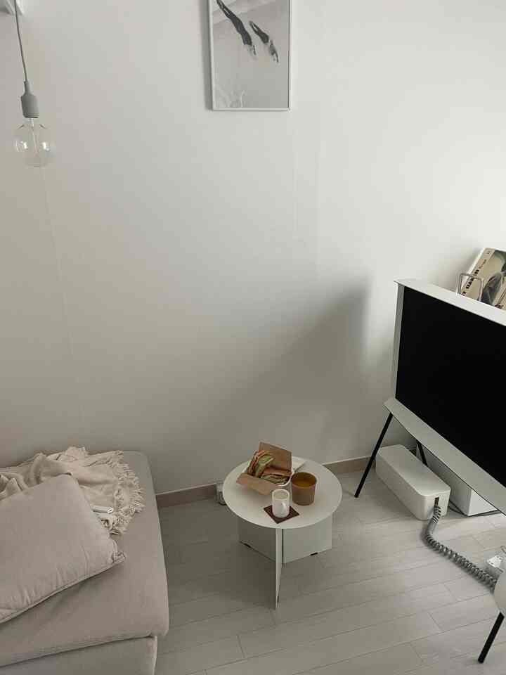 White and beige toned single household living room featuring simple, natural sofa and coffee table with cozy ambiance