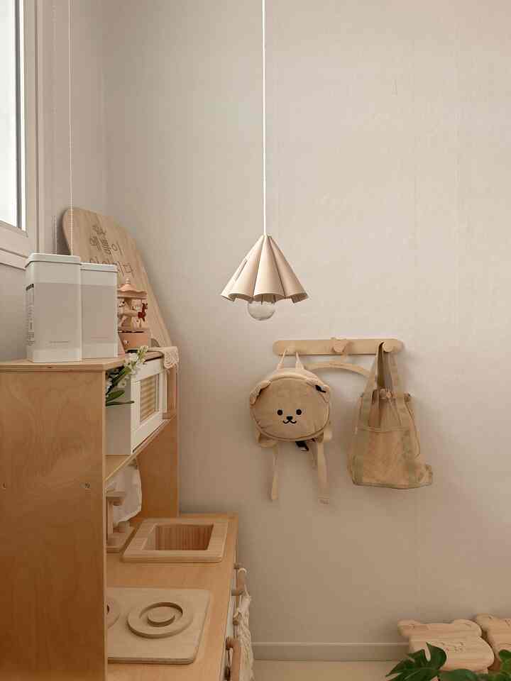 Beige and wood tone kids' room featuring wooden play kitchen and pendant light with a natural atmosphere
