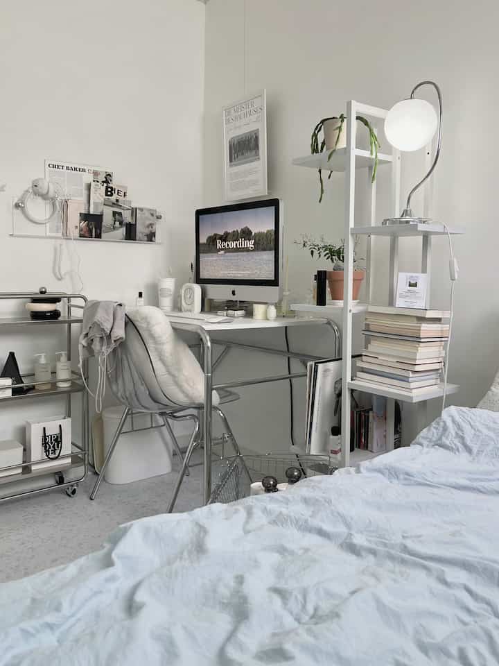 White and light gray toned bedroom featuring a desk and metal chair in a clean, mid-century modern style with an open atmosphere