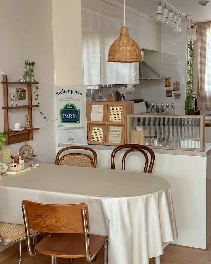 Small kitchen and dining area in wood tone and white colors featuring rattan chairs and fabric tablecloth with natural atmosphere