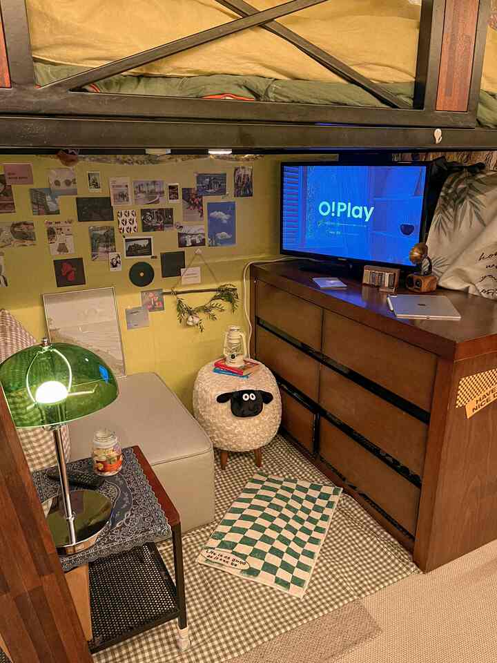 黄色と茶色のトーンの狭い寝室、二段ベッドとダークブラウンのチェスト、多様な壁飾りが配された印象的な空間