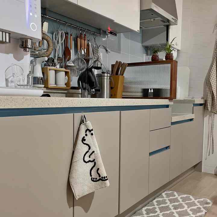 ベージュとグレーのトーンのキッチン、調理器具とタオルが整えられた自然な雰囲気のインテリア