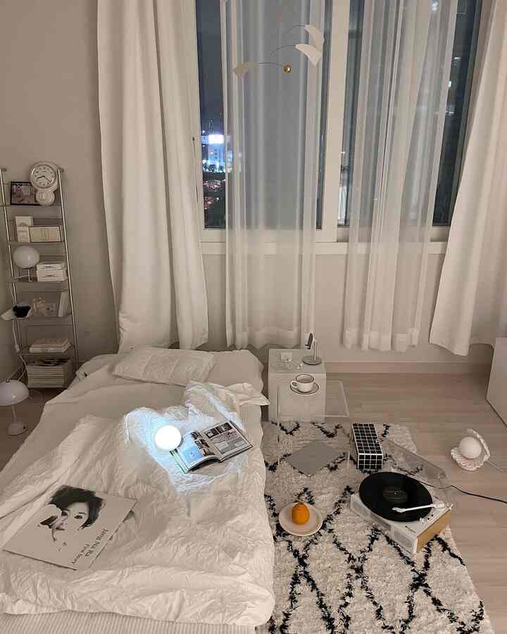 White and beige toned bedroom space with low bed and turntable, creating a neat and cozy atmosphere