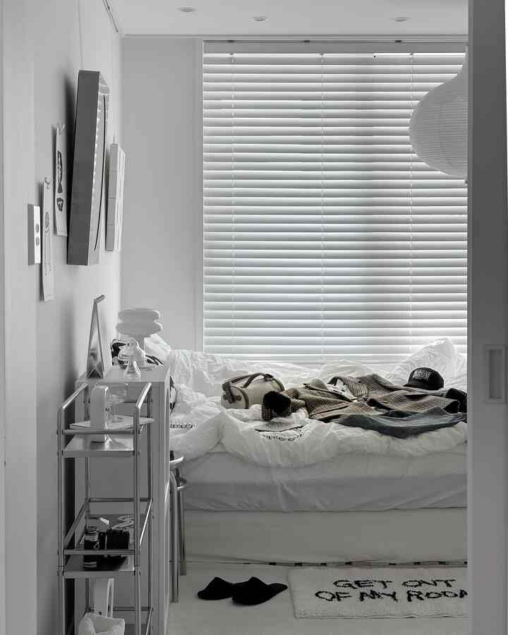 White-toned small bedroom featuring large blinds and white bedding, creating a clean and modern atmosphere