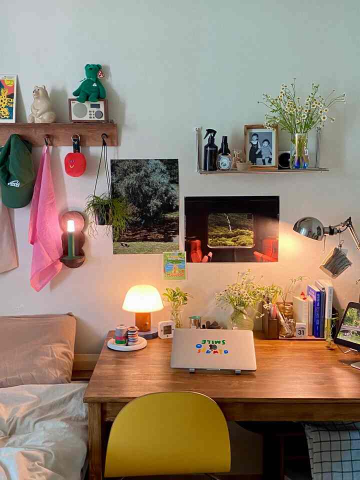 Natural wood tone bedroom home office with yellow chair, desk featuring laptop and plants creating warm ambiance