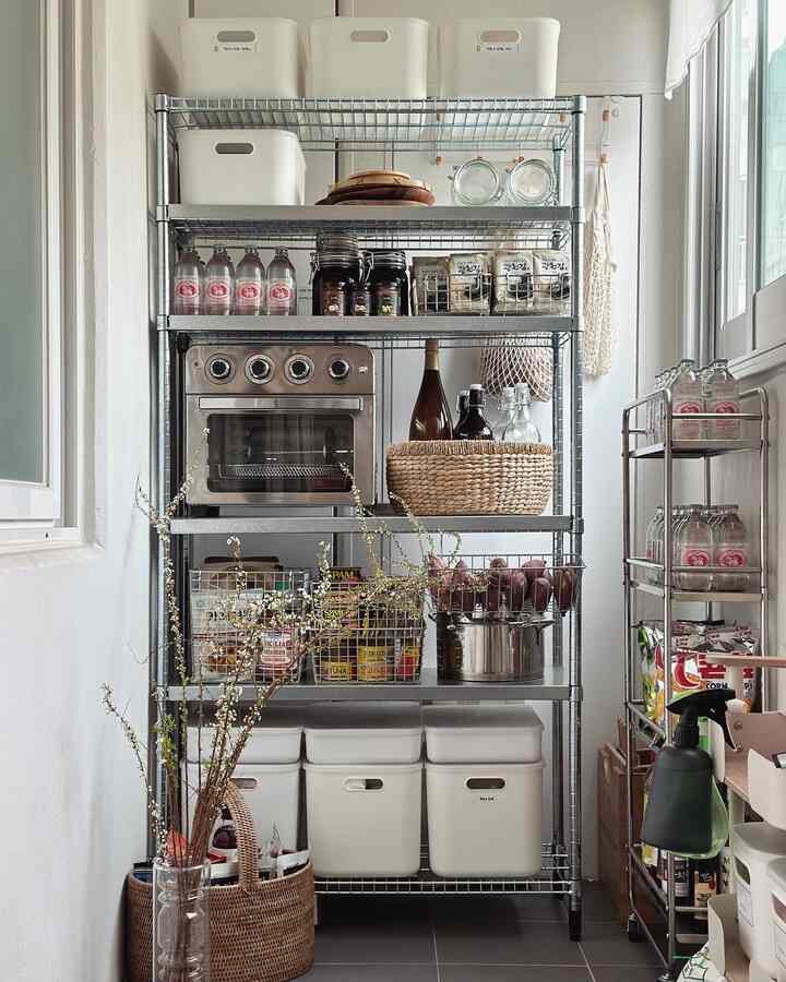 Narrow pantry space with white and stainless steel tones, organized storage containers and an oven neatly arranged in a utility kitchen area