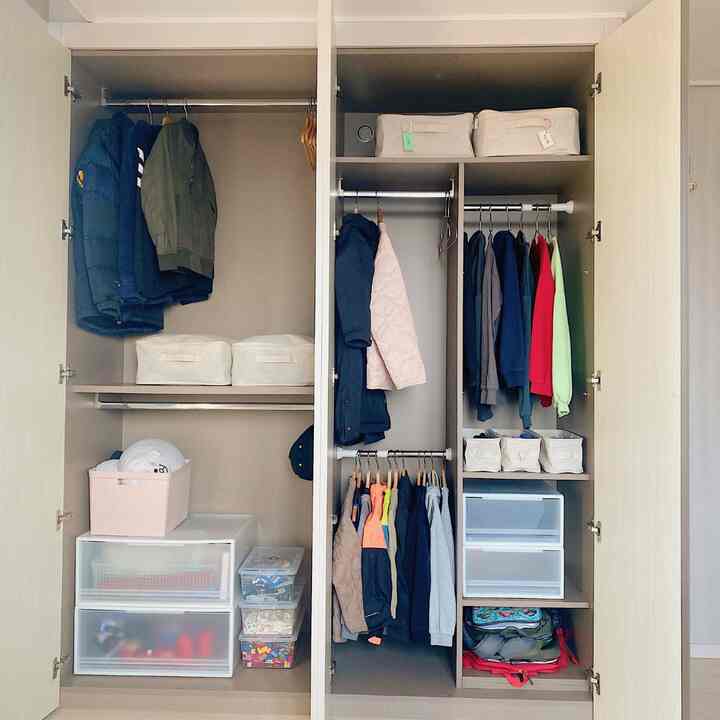白とグレーのトーンのクローゼット、子供服と収納ボックスが整頓された印象的な空間