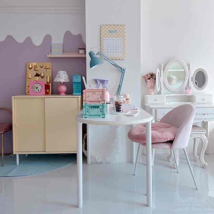 A white and pink bedroom with a desk and vanity arranged in a cozy, feminine setting
