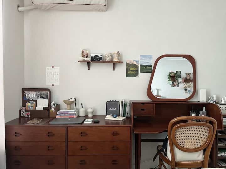 Calm brown wood-tone bedroom featuring a desk and vanity arranged neatly against white walls