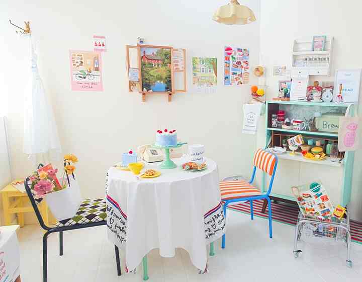 White-toned dining room featuring a round table and two colorful chairs with cozy retro ambiance